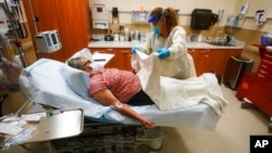 FILE - A nurse cares for a patient receiving an antibody infusion at the Upper Tanana Health Center, Sept. 22, 2021, in Tok, Alaska. 