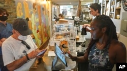 FILE - Owner Kymme Williams-Davis, right, takes orders at her Bushwick Grind Café after raises prices to keep up with inflation, in New York, Sept. 8, 2022.