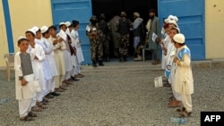 Afghan children hold flags as they stand outside their school to mark the beginning of new academic year in Kandahar, Sept. 7, 2022.