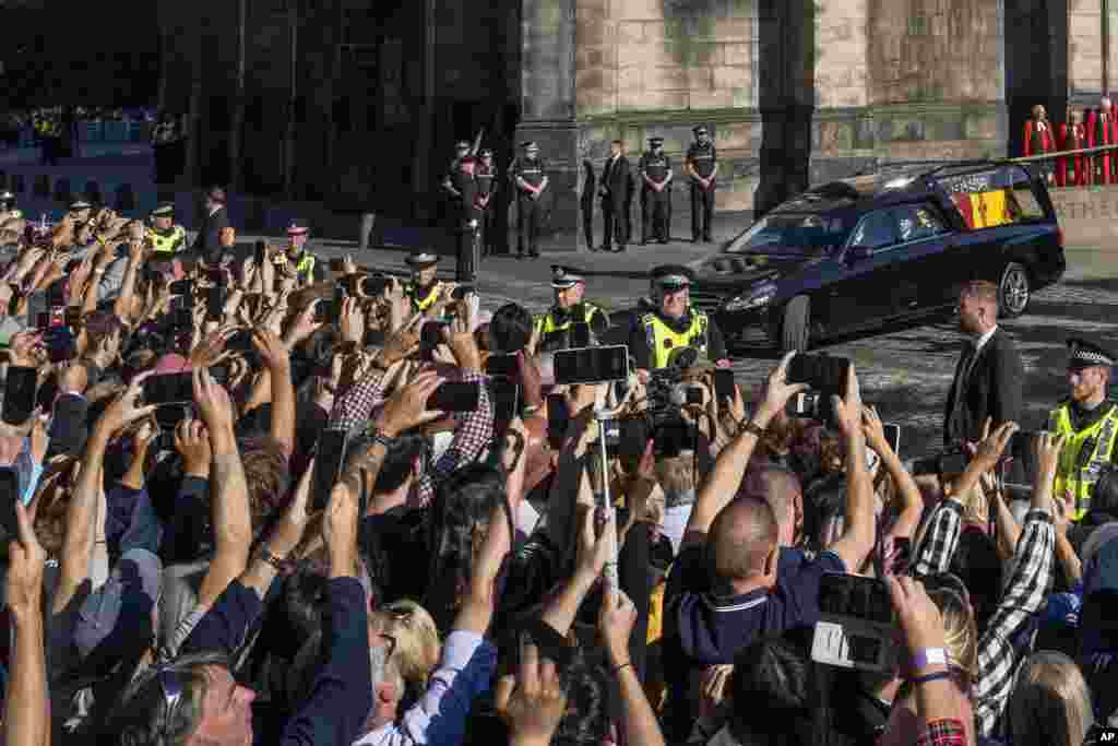 People take photos with their mobile phones as the Queens cortege with the hearse carrying Queen Elizabeth&#39;s coffin departs from St. Giles Cathedral en route to Edinburgh Airport in Edinburgh, Sept. 13, 2022.