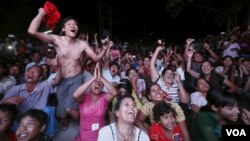 မန္တလေးမြို့ မဲဆန္ဒရှင်တွေ အမျိုးသားဒီမိုကရေစီအဖွဲ့ချုပ်ပါတီရုံးရှေ့က တီဗွီဖန်သားပြင်က ရွေးကောက်ပွဲရလဒ်တွေ စောင့်ကြည့်နေကြတဲ့ မဲဆန္ဒရှင်တွေရဲ့ စိတ်လှုပ်ရှားမှုမြင်ကွင်း။ (နိုဝင်ဘာ ၈၊ ၂၀၁၅)