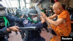 A protester clashes with riot police officers during a protest against the Asia-Pacific Economic Cooperation (APEC) Summit 2022, near the Democracy Monument in Bangkok, Thailand.