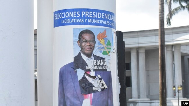 A campaign poster for Equatorial Guinea President Teodoro Obiang Nguema is pasted over a campaign poster of opponent Essono Ondo Andress, in Malabo, Nov. 17, 2022.