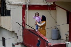 Faiqqa Homsi holds her daughter Maya, who was diagnosed with cancer, on her apartment balcony in the Mulawiya slum of the northern city of Tripoli, Lebanon, May 5, 2020.