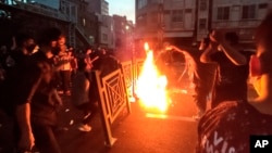 In this Sept. 21, 2022, photo, taken by an individual not employed by the Associated Press and obtained by AP outside Iran, protesters set a fire and block a street during a protest over the death of a woman who was detained over "unsuitable attire," in downtown Tehran.