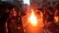 In this Sept. 21, 2022, photo, taken by an individual not employed by the Associated Press and obtained by AP outside Iran, protesters set a fire and block a street during a protest over the death of a woman who was detained over "unsuitable attire," in downtown Tehran.