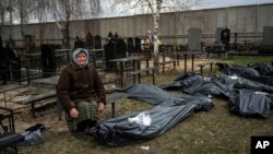 Bà Nadiya Trubchaninova, 70 tuổi, ngồi cạnh chiếc túi nhựa đựng thi thể của con trai bà là Vadym Trubchaninov, 48 tuổi, người đã bị binh lính Nga giết chết ở Bucha vào ngày 30/3, ở ngoại ô Kyiv, Ukraine, ngày 12/4/2022.
