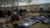 FILE - Nadiya Trubchaninova, 70, sits next to a bag containing the body of her son, who was killed by Russian soldiers on March 30, 2022, near Kyiv, Ukraine, April 12, 2022. Experts from several countries are investigating who can be prosecuted for crimes of aggression.