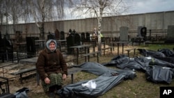 FILE - Nadiya Trubchaninova, 70, sits next to a bag containing the body of her son, who was killed by Russian soldiers on March 30, 2022, near Kyiv, Ukraine, April 12, 2022. Experts from several countries are investigating who can be prosecuted for crimes of aggression.
