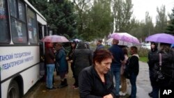 2022年9月23日星期五，人们在乌克兰卢甘斯克的移动投票站前排队参加全民投票。