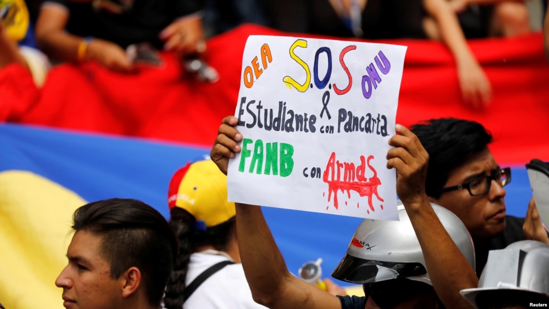 Un partidario de la oposición se cubre la boca con la palabra "Venezuela" y lleva una pancarta donde se lee "OEA, ONU, S.O.S, en una manifestación contra el presidente de Venezuela, Nicolás Maduro, en Caracas, Venezuela, el 2 de junio de 2017.