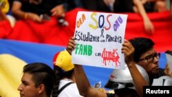 Un partidario de la oposición se cubre la boca con la palabra "Venezuela" y lleva una pancarta donde se lee "OEA, ONU, S.O.S, en una manifestación contra el presidente de Venezuela, Nicolás Maduro, en Caracas, Venezuela, el 2 de junio de 2017.