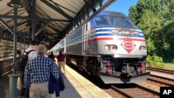 Commuters wait to board an arriving Virginia Railway Express commuter train, Sept. 14, 2022, at the Crystal City station in Arlington, Virginia.