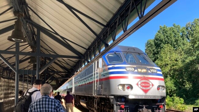 Commuters wait to board an arriving Virginia Railway Express commuter train, Sept. 14, 2022 at the Crystal City station in Arlington, Va.