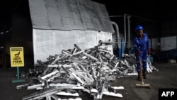 Un ouvrier balaie des déchets d'aluminium automobile fraîchement recyclés dans l'usine Romco de Lagos, le 26 août 2022.