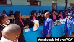 Amalunga eZim Mbokodo Women's Group besipha isipho semvunulo kumatnombazana aweMzinyathini High School