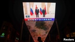 FILE - A giant screen broadcasts news footage of Chinese President Xi Jinping and Russian President Vladimir Putin posing for pictures during a meeting on the sidelines of the Shanghai Cooperation Organization (SCO) summit in Uzbekistan, in Beijing, China, Sept. 16, 2022.