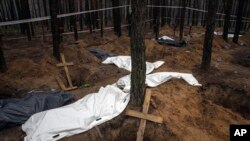 FILE - Bags with dead bodies are seen during the exhumation in the recently retaken area of Izium, Ukraine, Sept. 16, 2022.