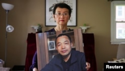 资料照片：中国维权律师丁家喜的妻子罗胜春在纽约家中手举着丈夫的照片。(2022年7月28日）