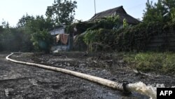 FILE: This photograph, taken Sept. 16, 2022. shows a hose pumping water from a water-damaged house in the town of Kryvyi Rih, where dozens of homes were flooded after a Russian attack damaged a dam upstream on Sept. 14, 2022.