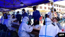 FILE - People queue to undergo nucleic acid tests for COVID-19 in Lhasa, in China's western Tibet Autonomous Region, Aug. 9, 2022.