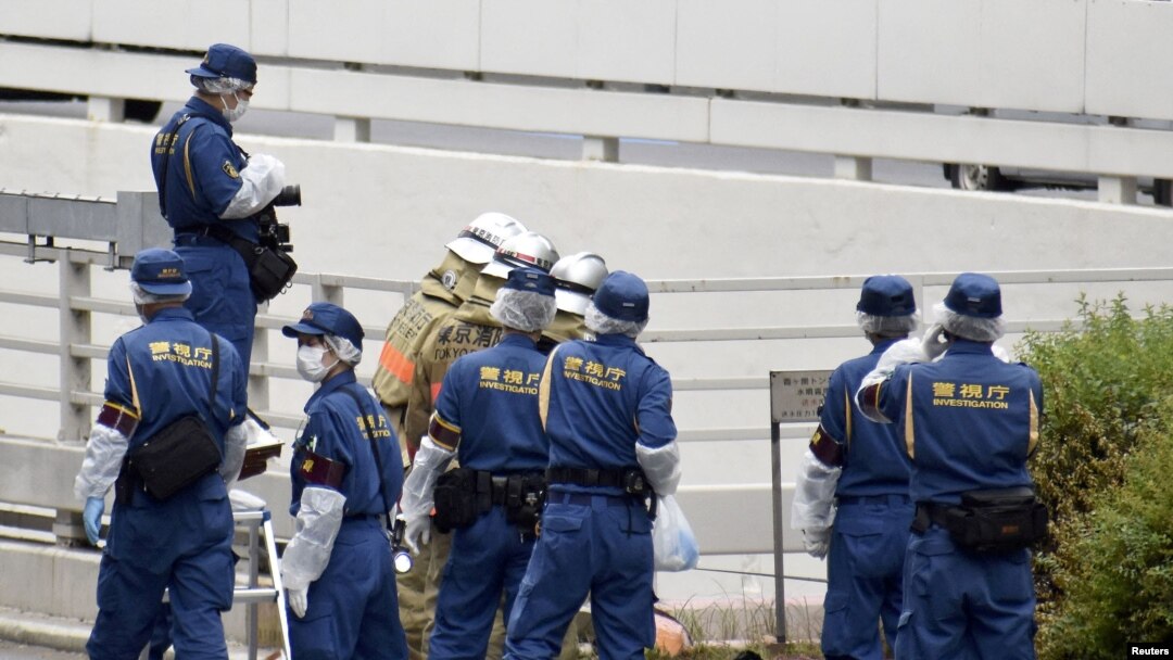Police officers and firefighters investigate the site where a man protesting a state funeral for former Japanese Prime Minister Shinzo Abe set himself on fire, in Tokyo, Japan Sept. 21, 2022.
