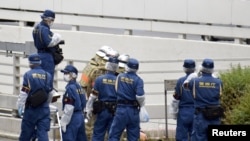 Police officers and firefighters investigate the site where a man protesting a state funeral for former Japanese Prime Minister Shinzo Abe set himself on fire, in Tokyo, Japan Sept. 21, 2022.