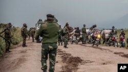 FILE: People walk on the road near Kibumba, north of Goma, Democratic Republic of Congo, as they flee fighting between Congolese forces and M23 rebels in North Kivu, Tuesday May 24, 2022.