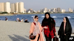 FILE - Women walk on the shore of the Persian Gulf Martyrs' Lake in Tehran, July 6, 2019. Some women in Iran have been taking off mandatory headscarves, or hijabs, in public, risking arrest.