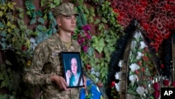 FILE: A Ukrainian soldier holds a photo of Olga Simonova, 34, a Russian woman who was killed in the Donetsk region while fighting on Ukraine's side in the war, in Kyiv, Ukraine, Sept. 16, 2022. 