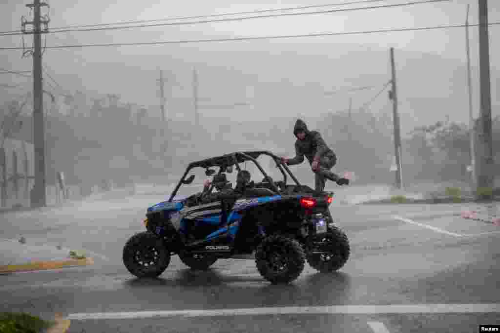A man jumps into an all terrain vehicle as Hurricane Fiona made landfall in Ponce, Puerto Rico, Sept. 18, 2022. 