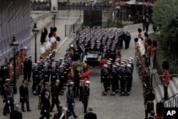 The coffin of Queen Elizabeth II is loaded on to a gun carriage pulled by Royal Navy soldiers to go from Westminster Hall for her funeral service in Westminster Abbey in central London, Sept. 19, 2022.