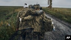 A Ukrainian soldier helps a wounded fellow soldier on the road in the freed territory in the Kharkiv region, Ukraine, Sept. 12, 2022.