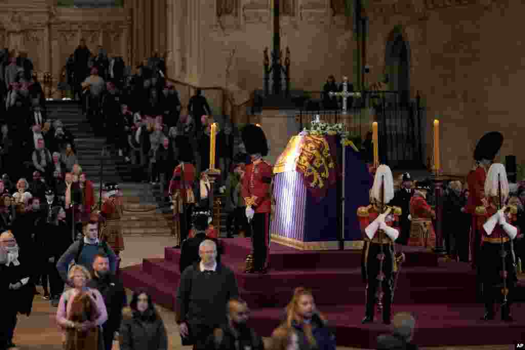A ray of sun shines on the coffin as members of the public file past the coffin of Queen Elizabeth II, draped in the Royal Standard with the Imperial State Crown and the Sovereign&#39;s orb and sceptre, lying in state on the catafalque in Westminster Hall in London, Sept. 18, 2022.