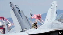 FILE - U.S. soldier checks the F/A-18 Super Hornet fighter jet on the deck of the aircraft carrier USS Ronald Reagan in Busan, South Korea, Sept. 23, 2022.