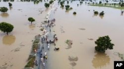 Des sinistrés marchent dans les eaux de crue après de fortes pluies à Hadeja, au Nigeria, lundi 19 septembre 2022.