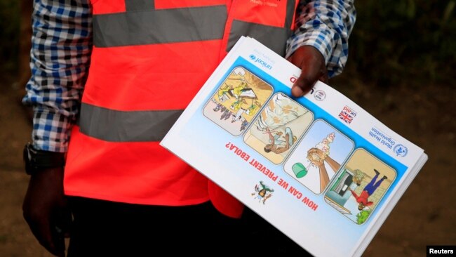 FILE - An Ugandan health worker shows an informational flyer on Ebola virus and how to prevent its spread to the community of Kirembo village, near the border with the DRC, in Kasese district, Uganda, June 15, 2019.