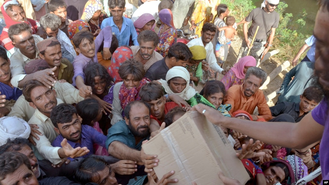 FILE - Displaced families get aid in Pakistan, Sept. 17, 2022. Flooding in Pakistan, the war in Ukraine, and violence and disasters in many parts of the world have caused the Office of the United Nations High Commissioner for Refugees' budget to balloon to almost $11 billion. 