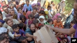 FILE - Displaced families get relief aid distributed by soldiers of Pakistan rangers in Balochistan province, Sept. 17, 2022. 