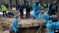 FILE- Emergency workers move a body during the exhumation in the recently retaken area of Izium, Ukraine, Sept. 16, 2022. It's unclear who was buried in many of the plots or how they died.