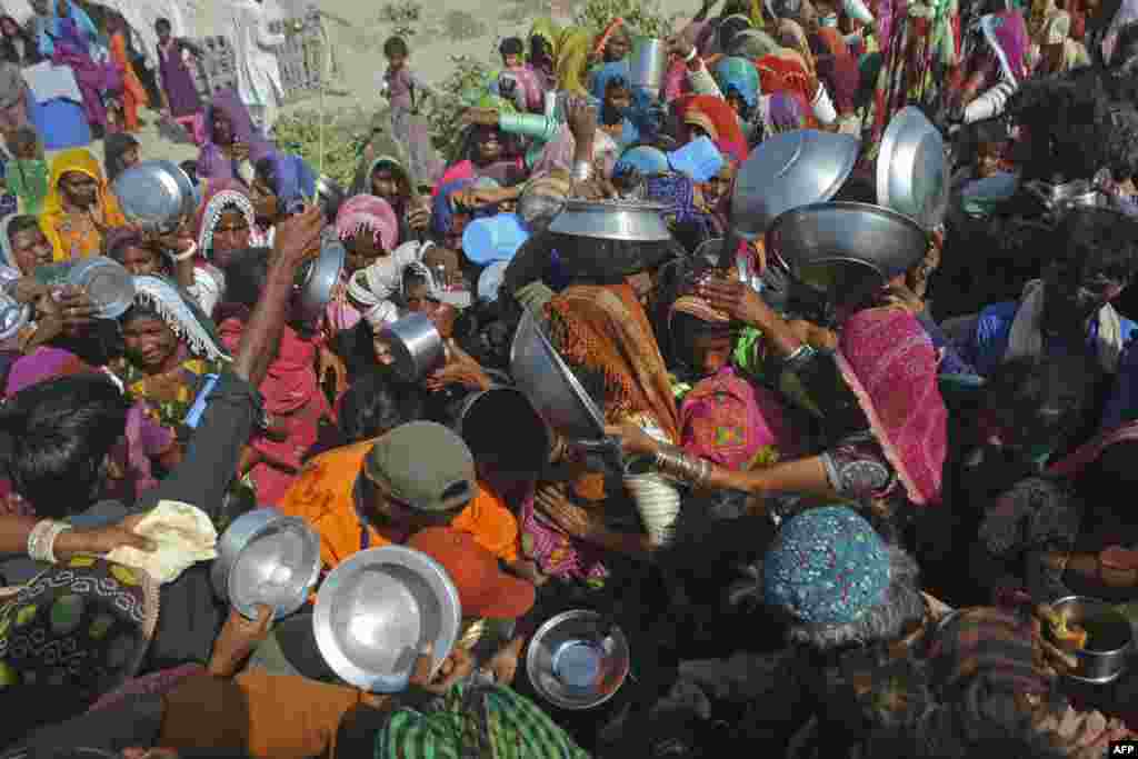 Internally displaced people gather to receive free food near their makeshift camp in the flood-hit Chachro of Sindh province, Pakistan.