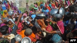 FILE - Internally displaced people gather to receive free food near their makeshift camp in the flood-hit Chachro of Sindh province, Pakistan, Sept. 19, 2022. 