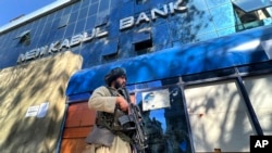 FILE - An armed Taliban guard stands outside a bank, in Kabul, Afghanistan, Feb. 13, 2022.