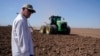 Farmer Larry Cox watches a tractor at work on a field at his farm Aug. 15, 2022, near Brawley, Calif. 