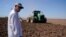 Farmer Larry Cox watches a tractor at work on a field at his farm Aug. 15, 2022, near Brawley, Calif. 