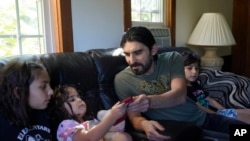 Mohammad Walizada, center right, who fled Afghanistan with his family, sits with three of his children, from the left, Zahra, 10, Hasnat, 3, and Mohammad Ibrahim, 7, Thursday, Sept. 15, 2022, at their home, in Epping, N.H. 