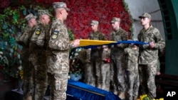 FILE: Servicemen pay their last respects at the coffin of Olga Simonova, 34, in a crematorium in Kyiv, Ukraine, Sept. 16, 2022.