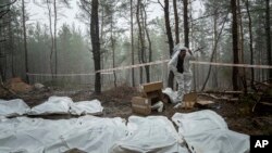 FILE- Bags with dead bodies found during the exhumation of a newly discovered mass burial site near the recaptured city of Izium, Ukraine, Sept. 16, 2022. 