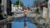 FILE - A woman stands on one of the streets of the gang-controlled Cite Soleil neighborhood of Port-au-Prince, Haiti.