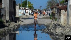 FILE - A woman stands on one of the streets of the gang-controlled Cite Soleil neighborhood of Port-au-Prince, Haiti.